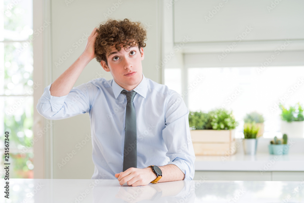 Young business man wearing a tie confuse and wonder about question. Uncertain with doubt, thinking with hand on head. Pensive concept.