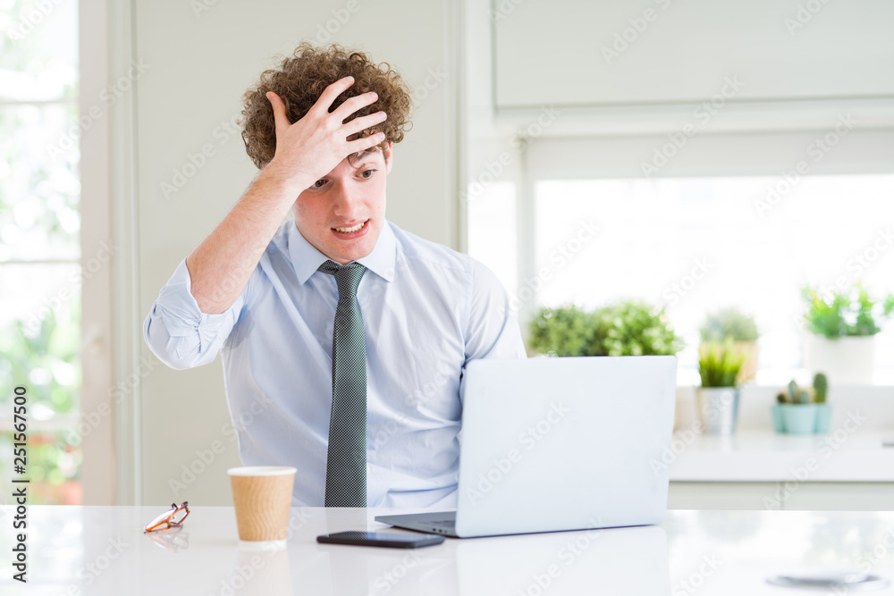 Young business man working with computer laptop at the office stressed with hand on head, shocked with shame and surprise face, angry and frustrated. Fear and upset for mistake.