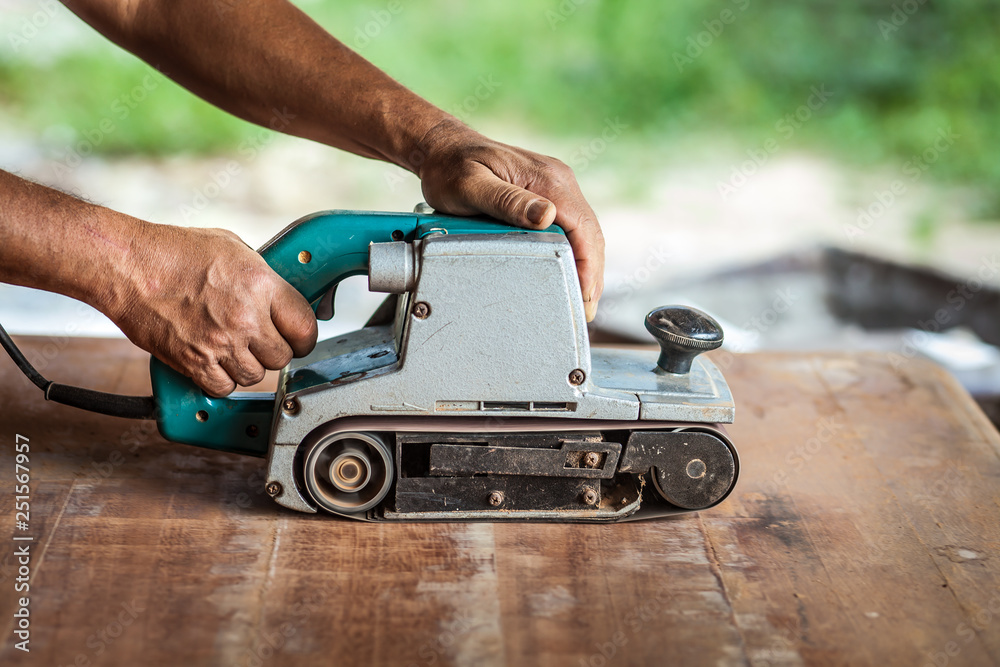 The carpenter uses power sander as a powerful tool in wood finishing. The carpenter uses power sander as a powerful tool in wood finishing.