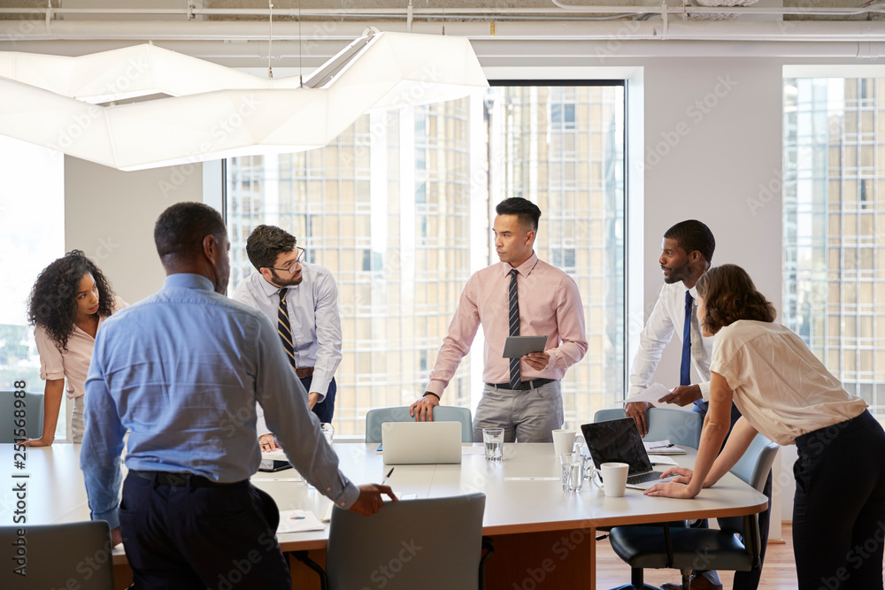 Group Of Business Professionals Standing At Meeting Around Table In Modern Office Group Of Business Professionals Standing At Meeting Around Table In Modern Office