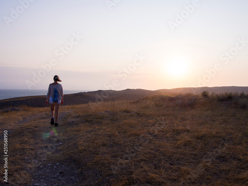 Woman walking towards the mountains at sunrise