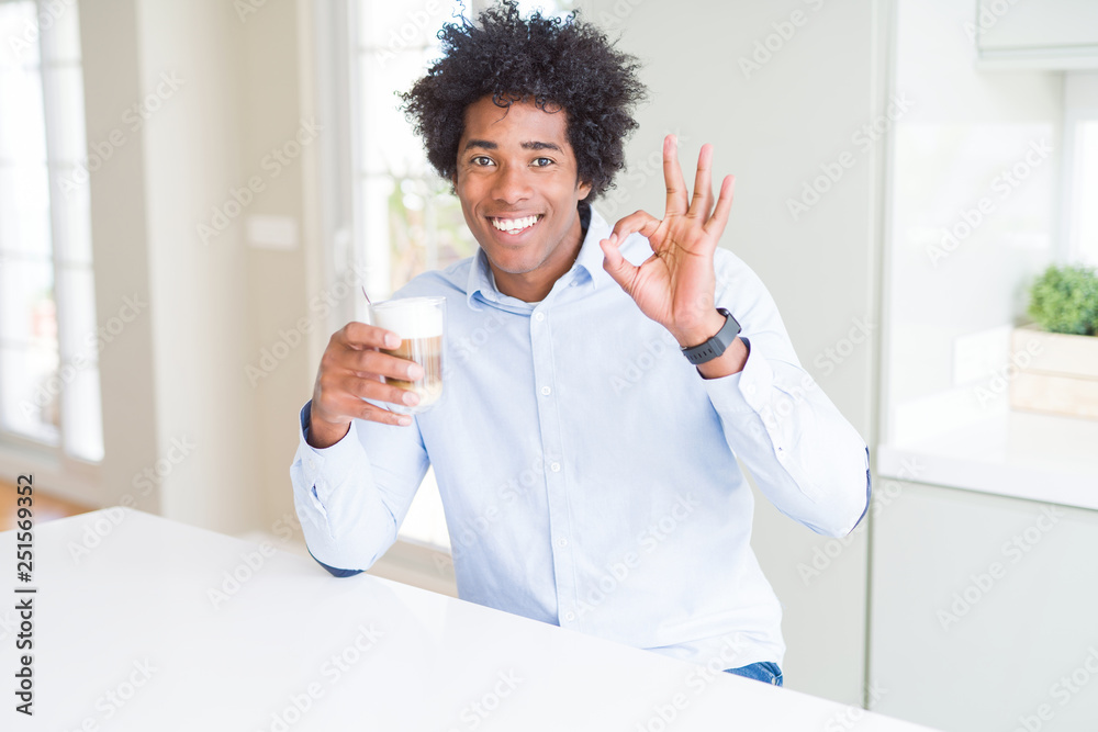 African American man with afro hair drinking a cup of coffee doing ok sign with fingers, excellent symbol