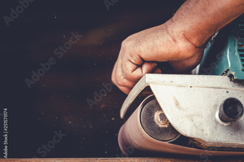 The carpenter uses power sander as a powerful tool in wood finishing. photo