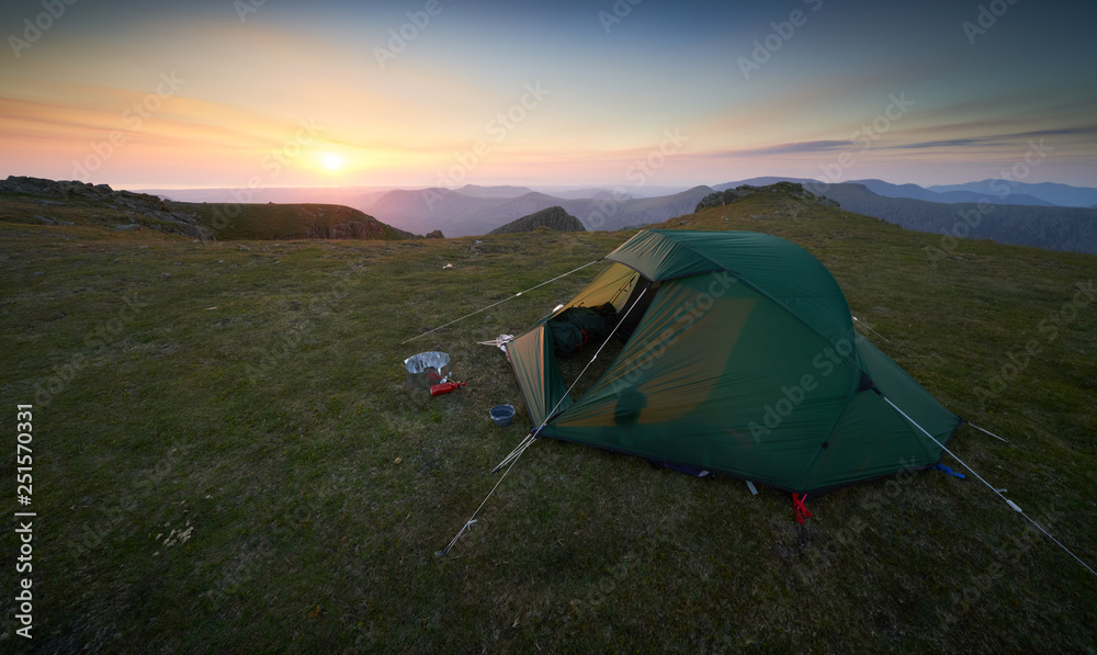 A tent pitched on the summit of Scoat Fell at sunset with views of Ennerdale in. the English Lake District.