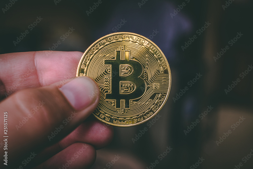 Some fingers holding a gold bitcoin Some fingers holding a gold bitcoin
