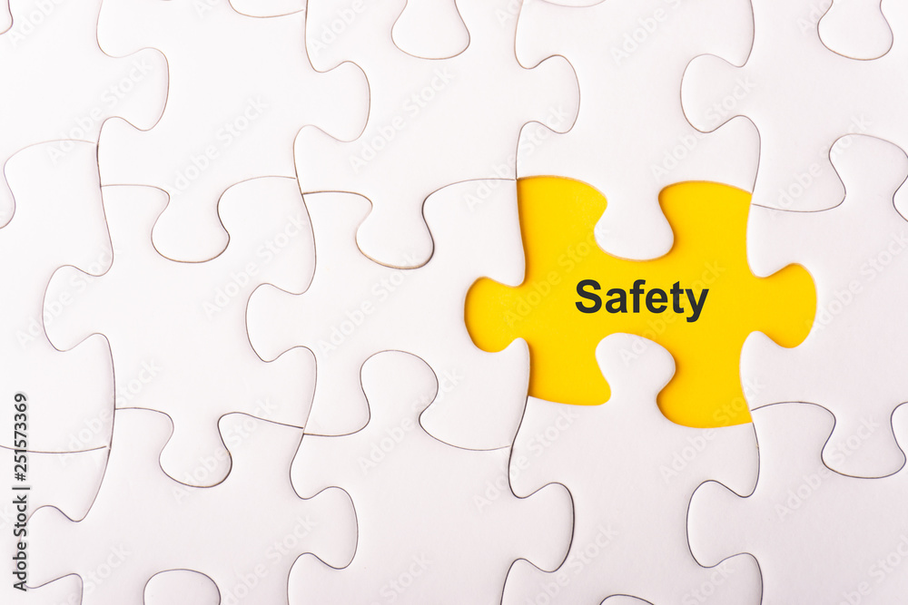 White jigsaw puzzle and missing pieces with words SAFETY selective focus and crop fragment White jigsaw puzzle and missing pieces with words SAFETY selective focus and crop fragment
