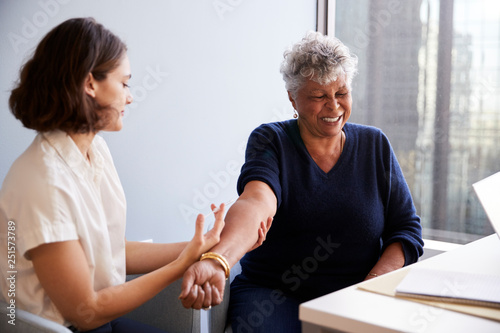 Senior Woman Being Vaccinated With Flu Jab By Female Doctor In Hospital Office photo