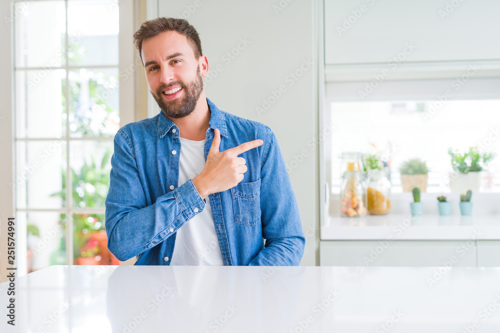 Handsome man at home cheerful with a smile of face pointing with hand and finger up to the side with happy and natural expression on face