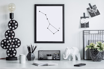 Stylish black and white home decor mock up. Creative desk with blank picture frame or poster, desk objects, office supplies, elephant figure and plants in design pots on a white background.