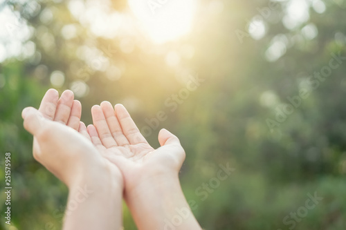 Woman open hand up to sunset sky and green blur leaf bokeh sun light abstract background.