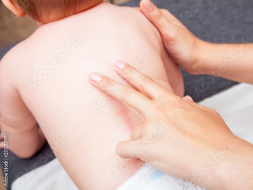 Little baby receiving chiropractic treatment of her back in a pediatric clinic