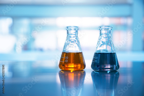 two glass flasks with orange and black solution in chemical science laboratory background