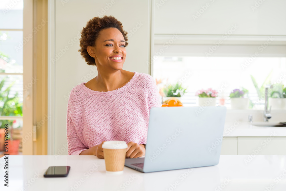 Young african american woman working using computer laptop looking away to side with smile on face, natural expression. Laughing confident. Young african american woman working using computer laptop looking away to side with smile on face, natural expression. Laughing confident.