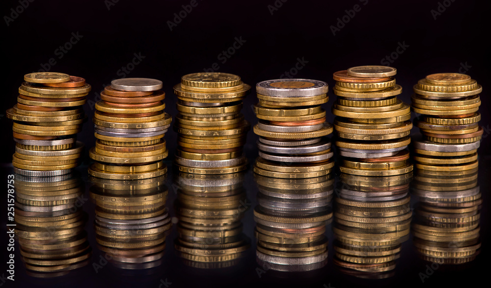 Stacks cf different country coins on black background Stacks cf different country coins on black background
