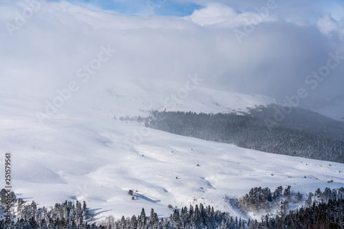 Magnificent winter mountain landscape: View over the mountain snow-capped peaks under the clouds Lago-Naki, The Main Caucasian Ridge, Russia