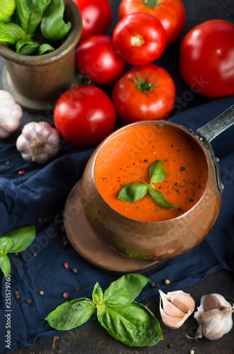 Traditional Italian tomato soup gazpacho with basil. Dark background.