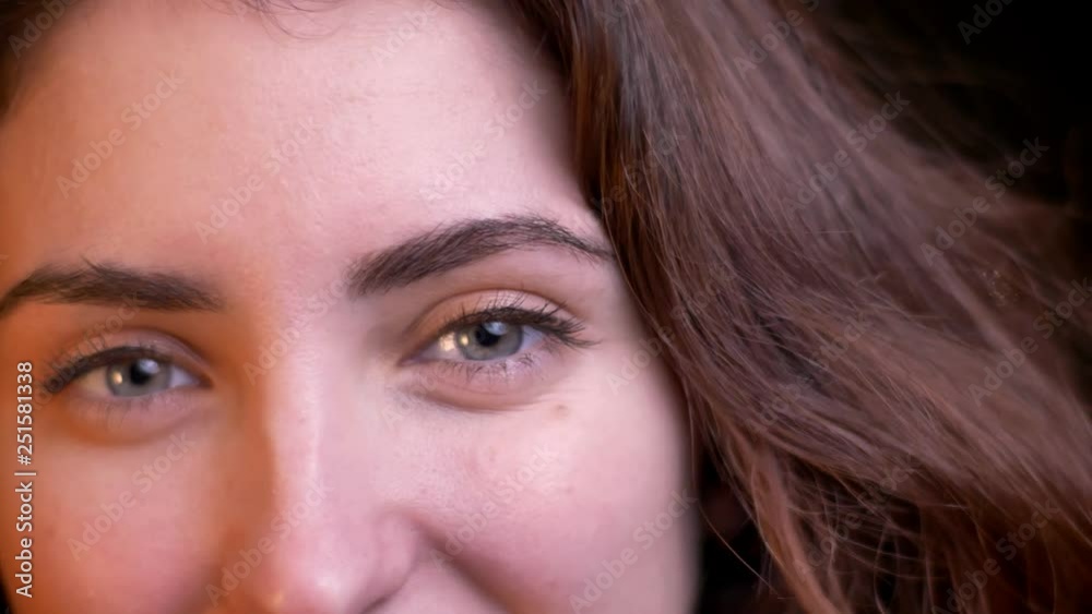 Close-up eye-portrait in profile of young caucasian girl watching joyfully into camera on blurred lights background. Close-up eye-portrait in profile of young caucasian girl watching joyfully into camera on blurred lights background.