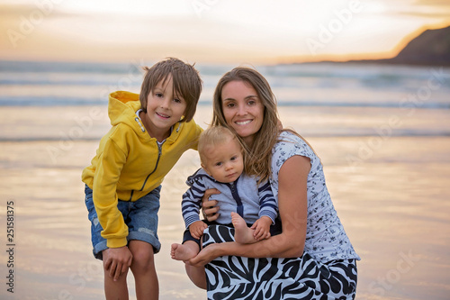 Young mother with her beautiful children, enjoying the sunset over the ocean on a low tide in Devon