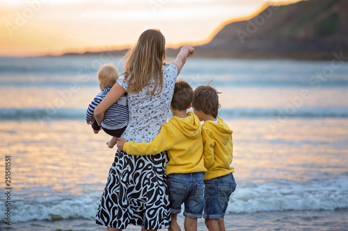 Young mother with her beautiful children, enjoying the sunset over the ocean on a low tide in Devon