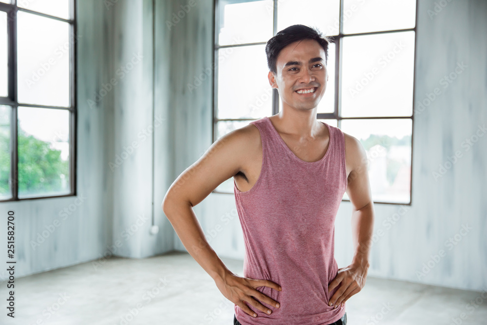 asian sport man smiling and his hands on hips. indoor exercise