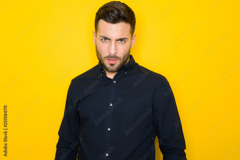 Obraz premium Young handsome man possing and modeling over yellow isolated background