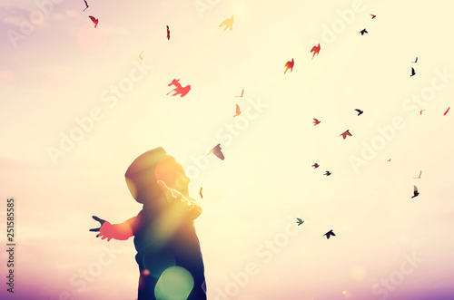 Freedom feel good and travel adventure concept. Copy space of silhouette man rising hands on sunset sky double exposure colorful bokeh and bird fly background.