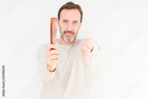 Senior man holding hair comb over isolated background with angry face, negative sign showing dislike with thumbs down, rejection concept
