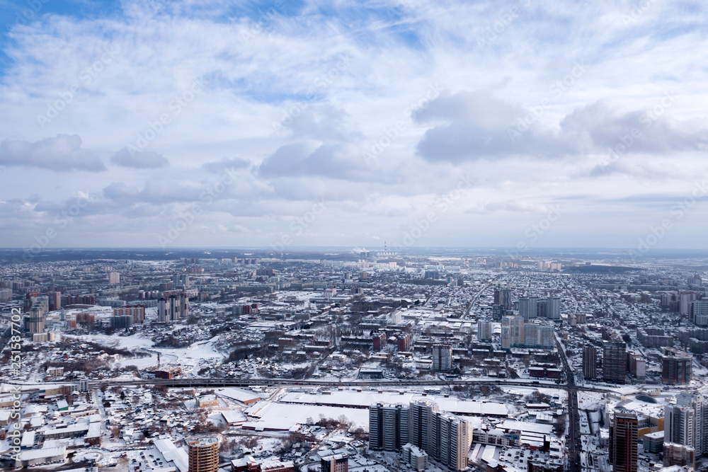 Winter landscape from a aerial view of the city of Novosibirsk in the haze with streets, small buildings, covered by snow and protruding pipe from which smoke comes