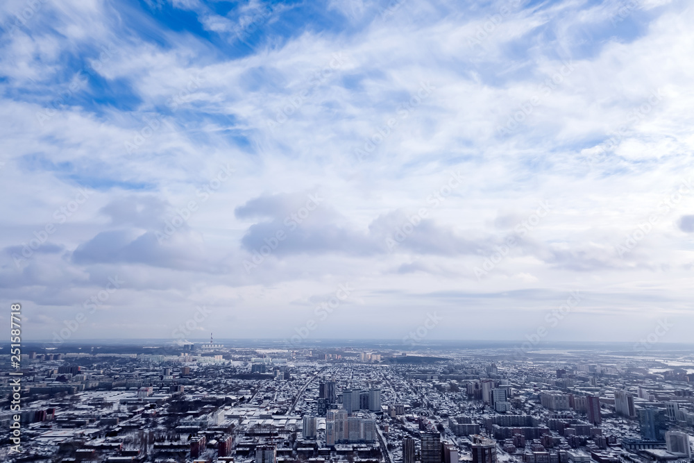 Winter landscape from a aerial view of the city of Novosibirsk in the haze with streets, small buildings, covered by snow and protruding pipe from which smoke comes