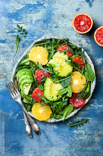 Citrus salad with mixed greens and blood orange. Vegan, vegetarian, clean eating, dieting, food concept. Blue stone background.