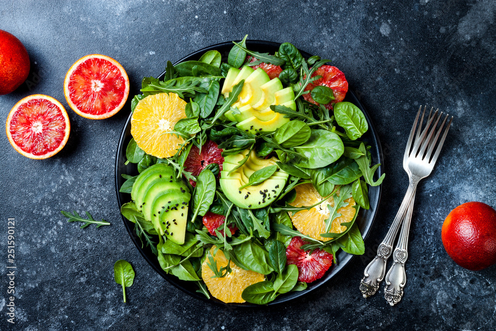 Citrus salad with mixed greens and blood orange on black ceramic plate. Vegan, vegetarian, clean eating, dieting, food concept. Dark stone background. Citrus salad with mixed greens and blood orange on black ceramic plate. Vegan, vegetarian, clean eating, dieting, food concept. Dark stone background.