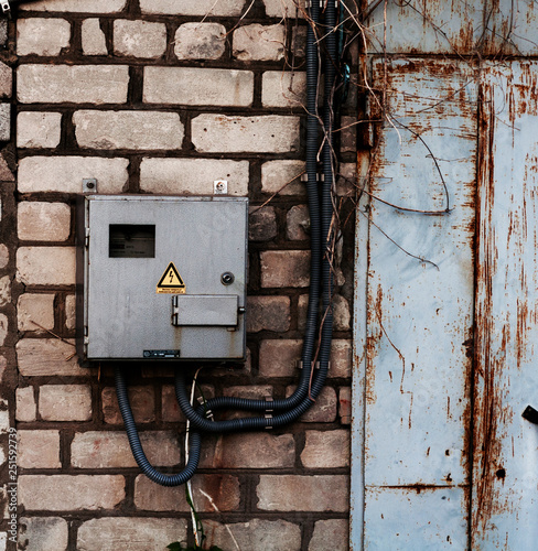 old electric meter in a protective box fortified on a brick wall with white brick