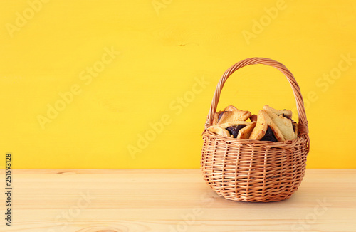 Purim celebration concept (jewish carnival holiday). Traditional hamantaschen cookies over wooden table
