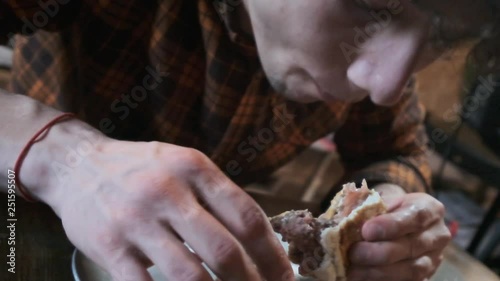 A stern bearded man aggressively and rudely eats sandwiches. Eats fast food. The concept of obesity society and poor nutrition. photo