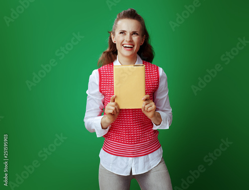smiling modern student woman with yellow book looking aside © Alliance
