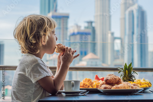 фотографія The boy is having breakfast on the balcony
