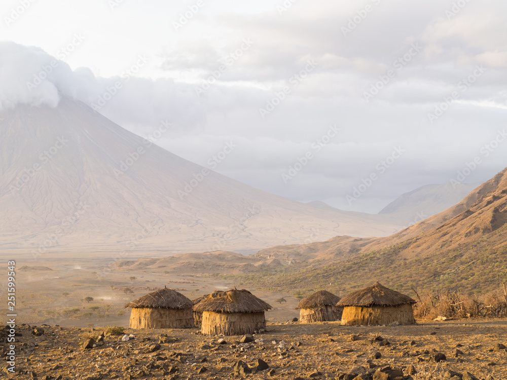 Maasai village in front of the Ol Doinyo Lengai (Mountain of God in the Maasai language), an active volcano in Arusha Region i the Northern Tanzania, Africa, at sunrise.