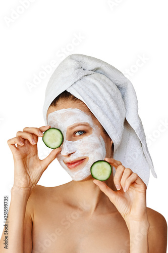 Beautiful young woman with facial mask on her face holding slices of cucumber. Skin care and treatment, spa, natural beauty and cosmetology concept, isolated over white background