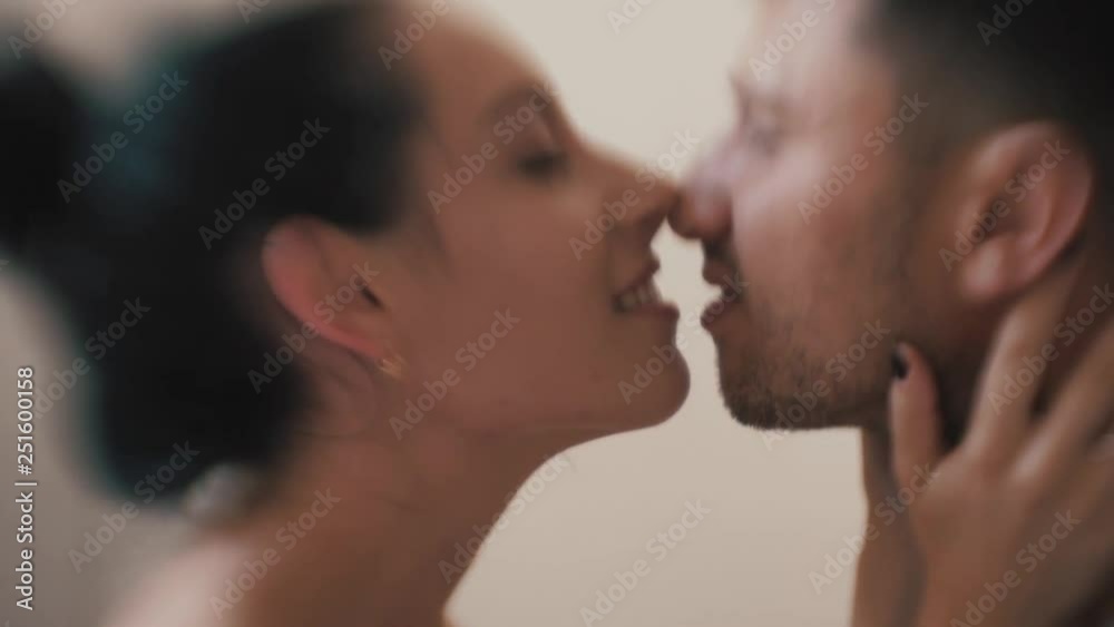 Young happy couple in love having fun together in bedroom at home, playful wife biting smiling husband ear, embracing, piggyback, man and woman playing childish in bed, enjoying funny intimate moments Young happy couple in love having fun together in bedroom at home, playful wife biting smiling husband ear, embracing, piggyback, man and woman playing childish in bed, enjoying funny intimate moments