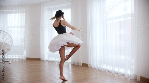 Young beautiful woman ballerina training in bright studio. Performing the pirouette