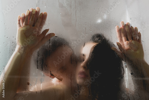 selective focus of passionate naked man kissing attractive woman in shower cabin photo