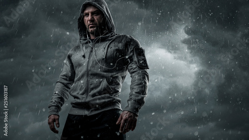 Dark, dramatic portrait of a runner standing in the rain with copy space