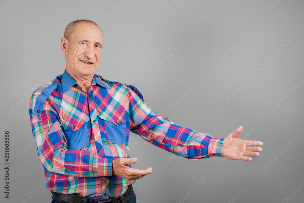 The elderly person point away. Serious Mature man pointing finger to the side, on grey background, copy space The elderly person point away. Serious Mature man pointing finger to the side, on grey background, copy space