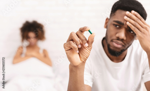 Upset black guy taking potency pill before sex with girlfriend photo