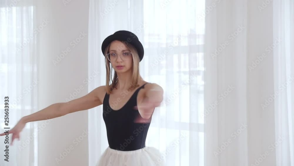 Young woman ballerina in black hat training in bright studio. Performing the pirouette Young woman ballerina in black hat training in bright studio. Performing the pirouette