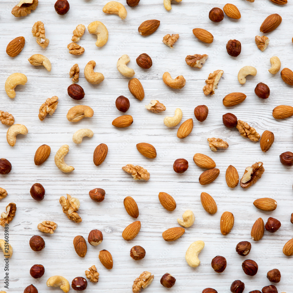 Mixed nuts (cashew, hazelnuts, walnuts, almonds) on white wooden table, top view. From above, overhead. Mixed nuts (cashew, hazelnuts, walnuts, almonds) on white wooden table, top view. From above, overhead.