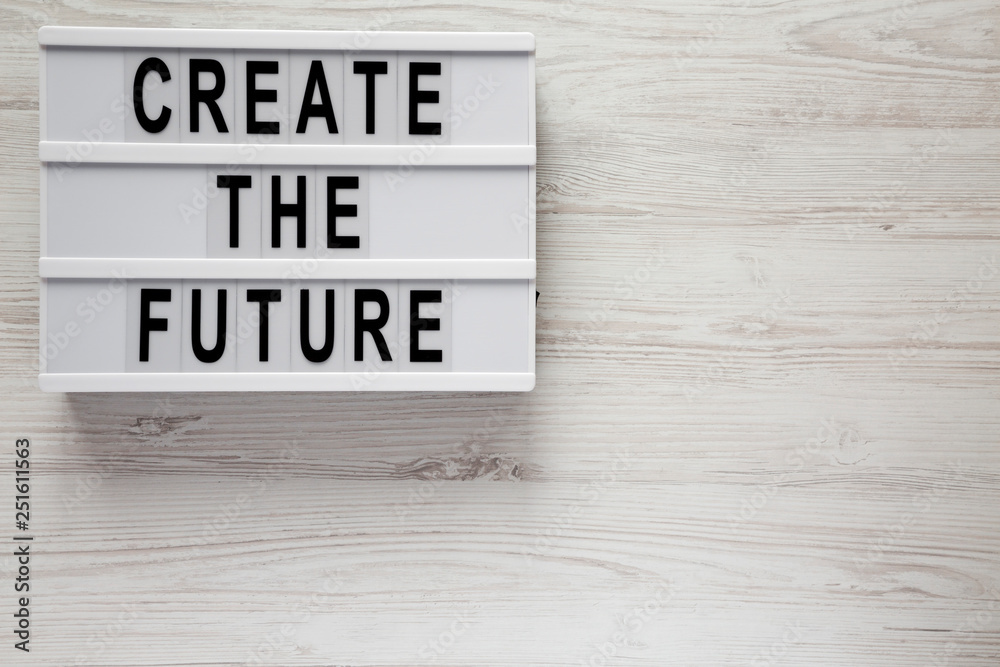 'Create the future' word on modern board on a white wooden surface, top view. From above, flat lay, overhead. Copy space.