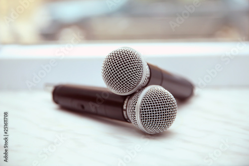 Two silver microphones isolated over white background . Two wireless microphones on the conference table.