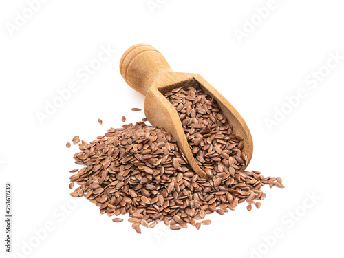 Pile and wooden scoop with linseeds or flax seeds seen obliquely from the side and isolated on white background