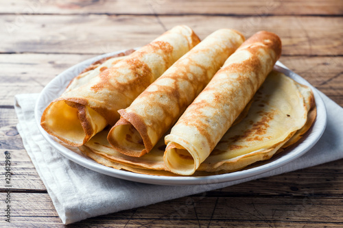 Thin pancakes on a plate. Wooden background. Close up.